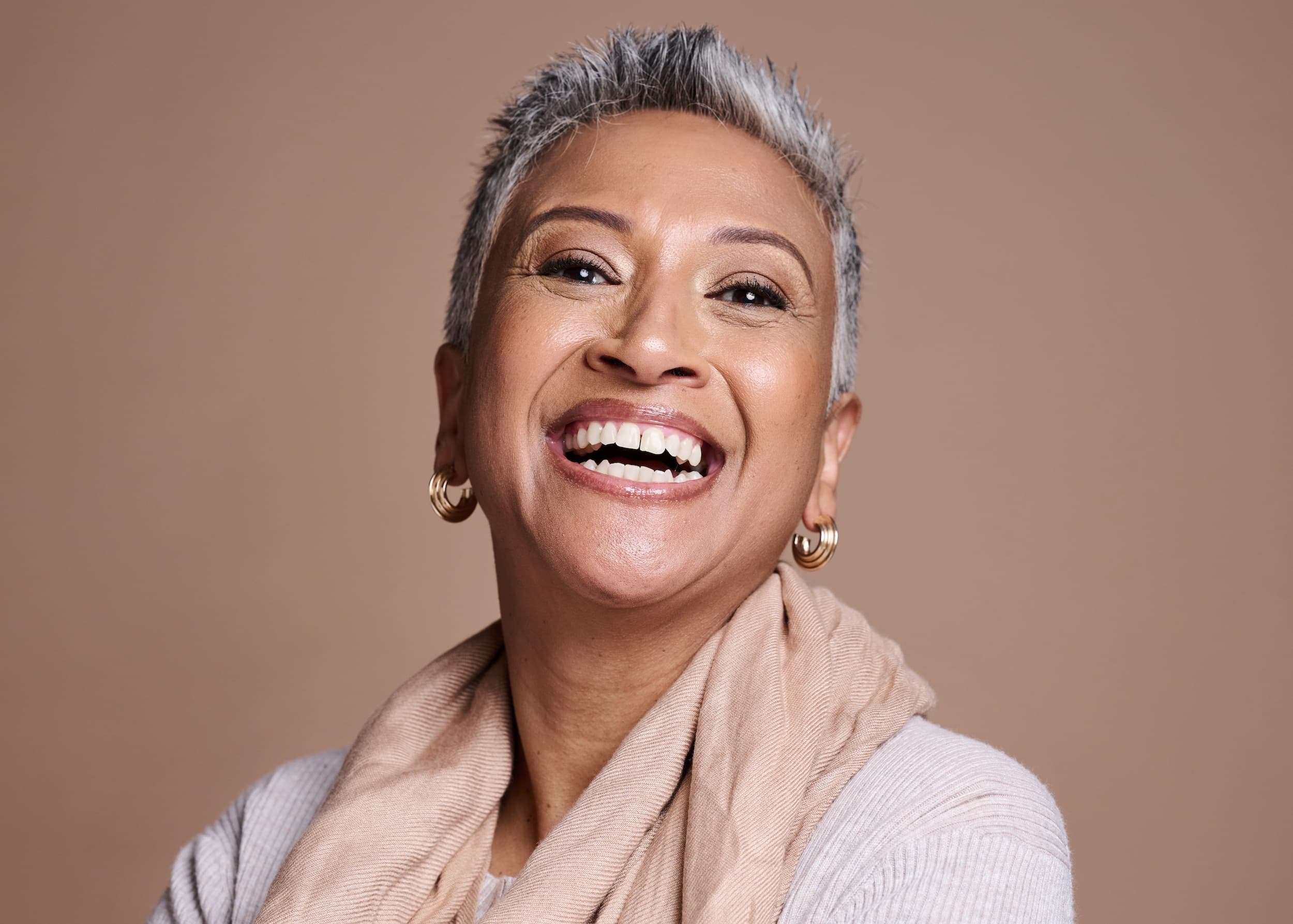 Confident mature woman laughing after dental bridge restoration at Esthetique Dentistry Ashburn