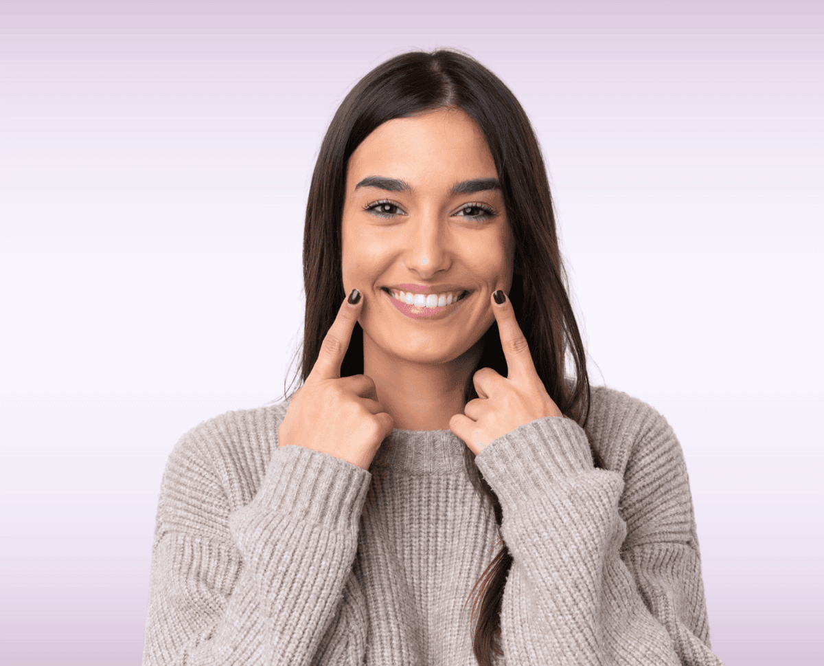 Woman smiling and pointing to her healthy teeth after oral cancer screening